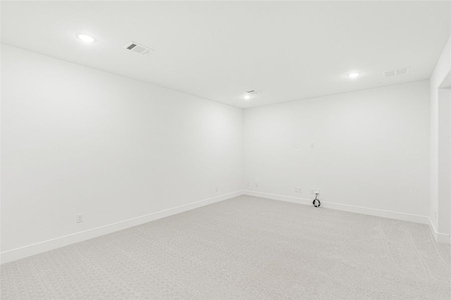 Empty room with white walls, light carpet, and recessed ceiling lights