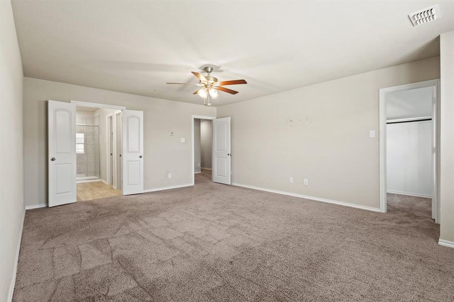 Unfurnished bedroom featuring light colored carpet, ensuite bath, and a ceiling fan Unfurnished bedroom featuring light colored carpet, ensuite bath, and a ceiling fan