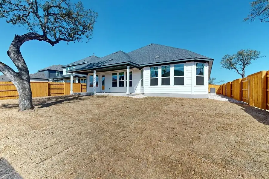 The property features a spacious rear yard with a wooden privacy fence and a mature tree