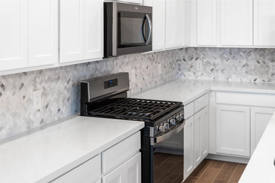 Showcased here is a Whirlpool gas range featuring a versatile center oval burner, paired with a steam microwave equipped with sensor cooking—all framed by an elegant tile backsplash.
