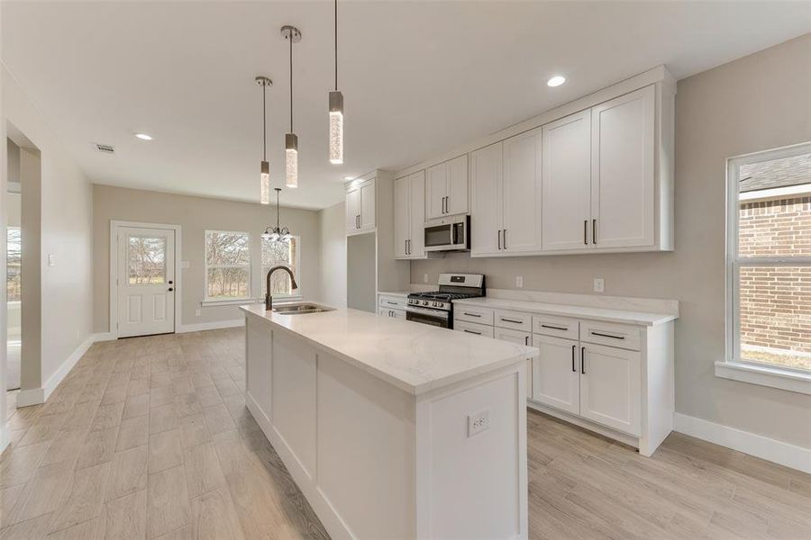 Kitchen with pendant lighting, stainless steel appliances, sink, and white cabinets