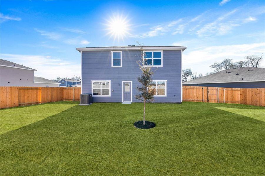 Rear view of property with central air condition unit and a yard