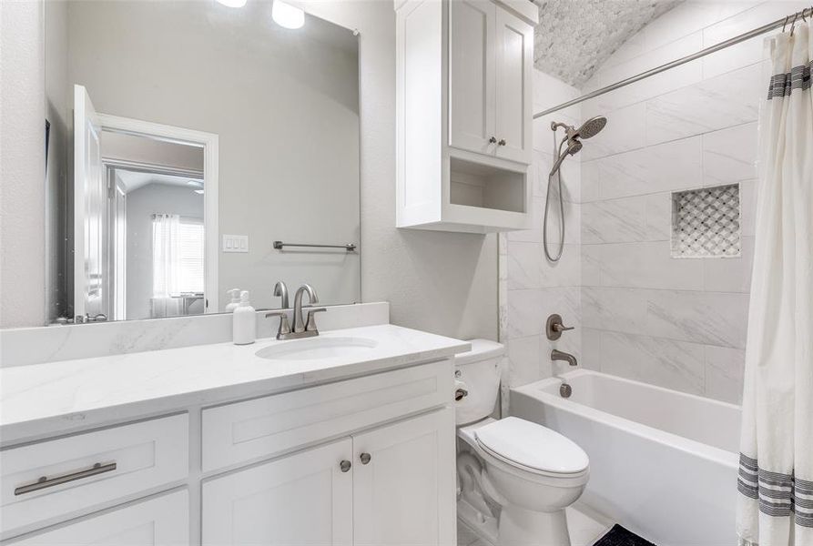 Full bath featuring shower / bath combo with shower curtain, vanity, and vaulted ceiling Full bath featuring shower / bath combo with shower curtain, vanity, and vaulted ceiling