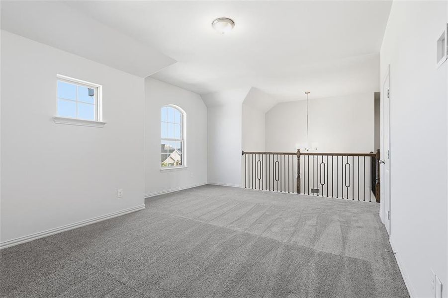 Additional living space featuring a chandelier, carpet flooring, and vaulted ceiling