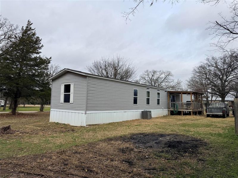 View of side of property featuring a yard and a wooden deck