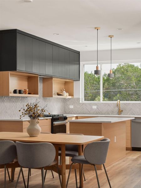 Kitchen with modern cabinets, decorative light fixtures, tasteful backsplash, light wood-style floors, and black gas range