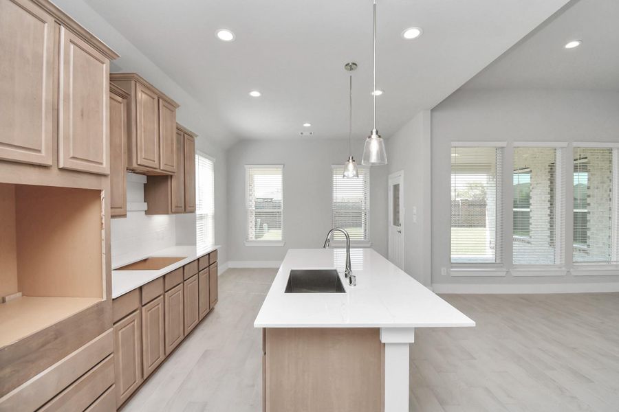This kitchen is truly a chef's dream! This haven Boasts high ceilings, recessed & pendant lighting, stained wood cabinets, granite countertops, stainless steel appliances, a modern tile backsplash.  All of this overlooks your expansive family room, creating a perfect space for culinary delights and family gatherings. Sample photo of completed home with similar floor plan. Actual colors and selections may vary.