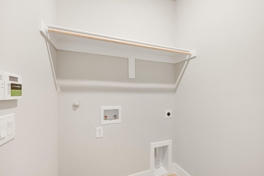 Laundry room with upper shelf, hanging rod, washer and dryer hookups, and gas or electric connections on white walls.