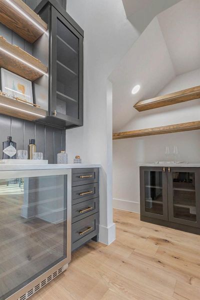 Designer butler’s pantry featuring custom cabinetry, glass-front storage, open shelving, and integrated refrigeration, offering both function and elevated style for entertaining.