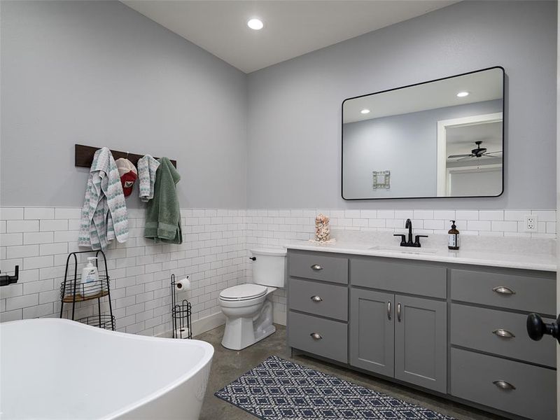 Bathroom featuring a soaking tub, tile walls, vanity, a wainscoted wall, and recessed lighting Bathroom featuring a soaking tub, tile walls, vanity, a wainscoted wall, and recessed lighting