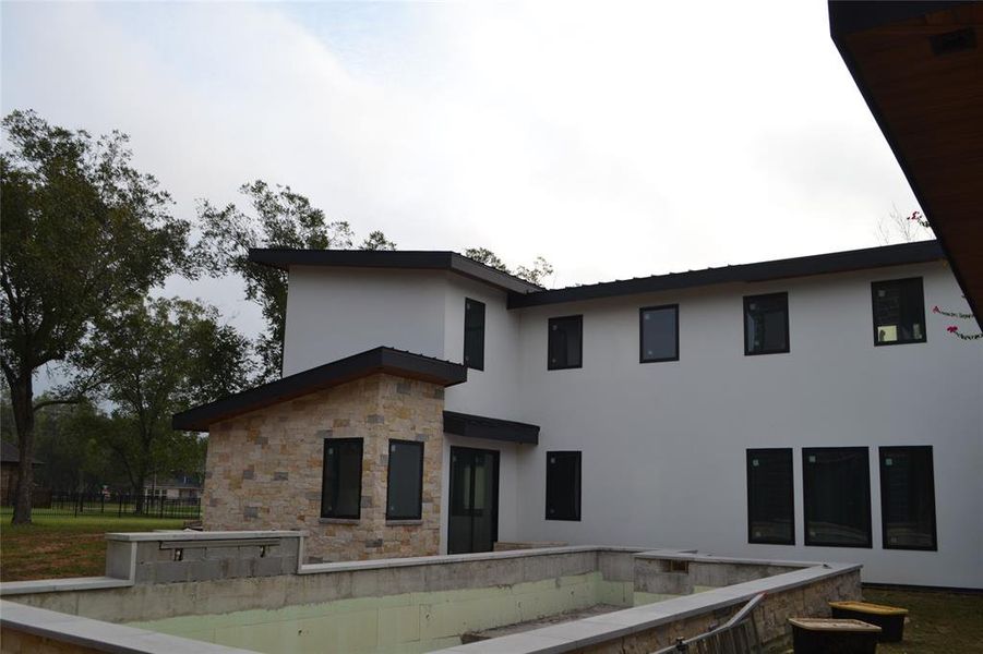 Rear view of house featuring stucco siding, a patio, and stone siding Rear view of house featuring stucco siding, a patio, and stone siding