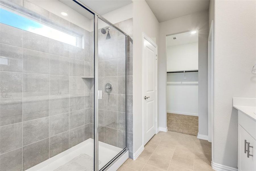 Bathroom featuring vanity, a walk in closet, a stall shower, and light tile patterned flooring