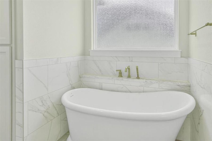 Bathroom with a freestanding bath, tile walls, plenty of natural light, and wainscoting