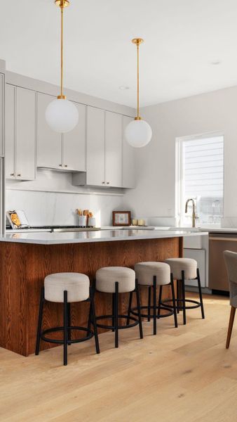 Kitchen with white cabinetry, a kitchen bar, decorative light fixtures, light wood-type flooring, and dishwasher