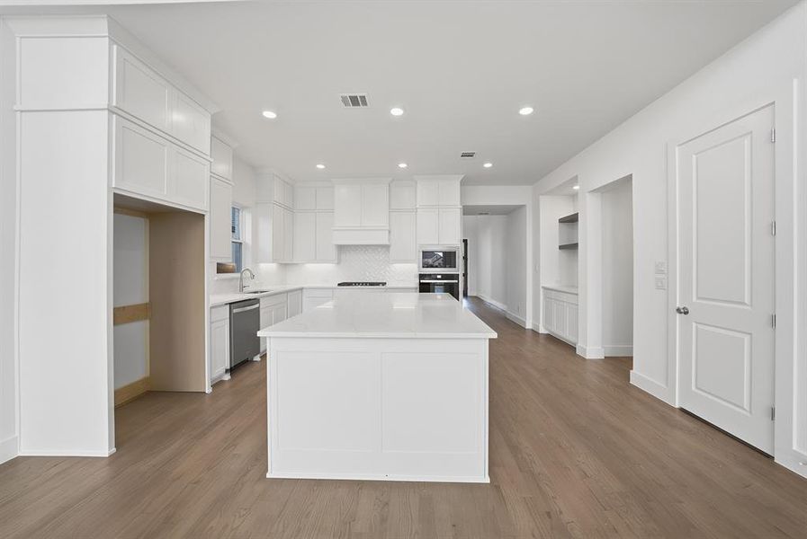 Kitchen with white cabinets, backsplash, a kitchen island, open shelves, and wall oven Kitchen with white cabinets, backsplash, a kitchen island, open shelves, and wall oven