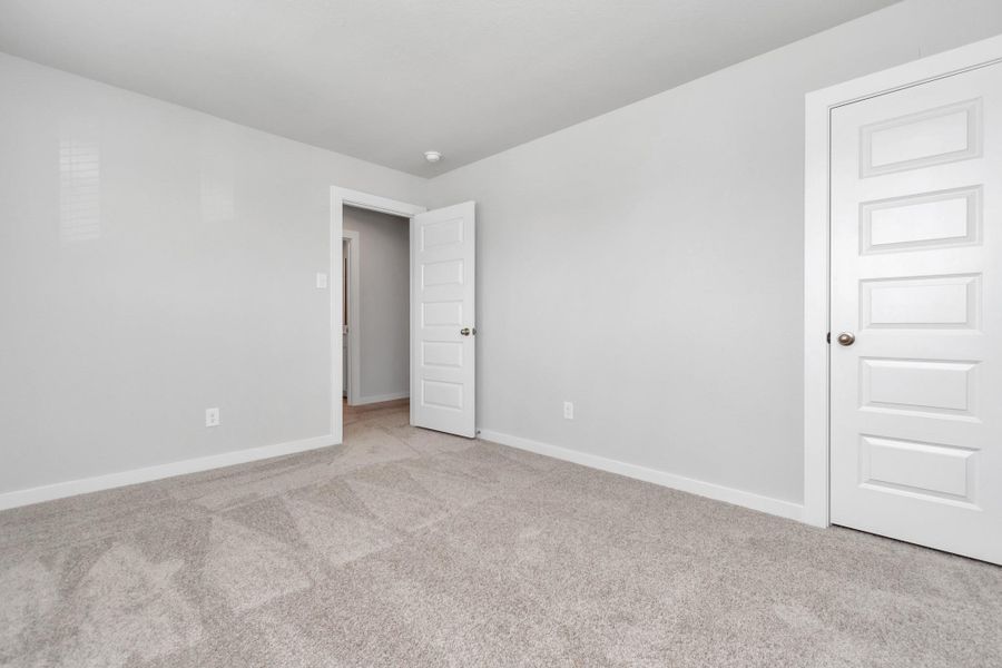 Secondary bedrooms showcase 5-panel doors adorned with modern hardware, large windows enhanced by privacy blinds, and spacious closets featuring sleek and contemporary finishes. Sample photo of completed home with similar floor plan. Actual colors and selections may vary.