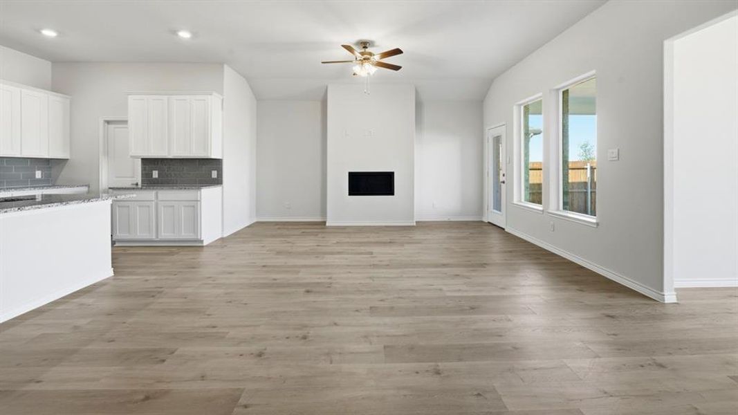 Open-concept living area featuring wood-finish flooring, a contemporary fireplace, and a ceiling fan