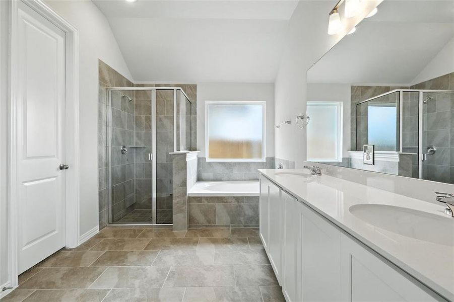 Bathroom with lofted ceiling, double vanity, a shower stall, and a garden tub