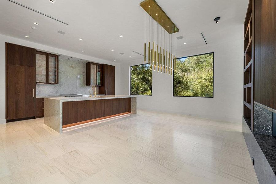 Kitchen featuring modern cabinets, glass insert cabinets, light stone counters, a center island with sink, and recessed lighting