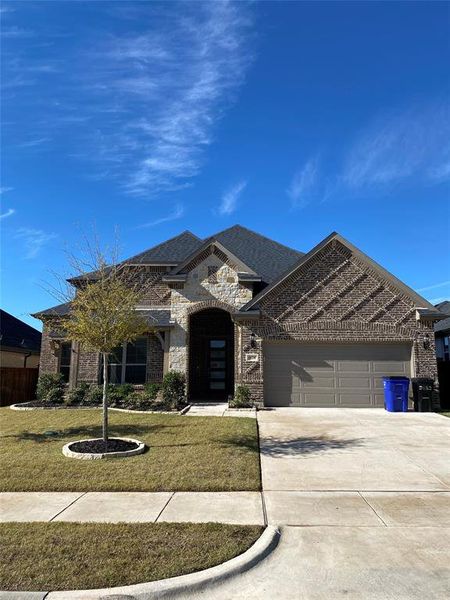 French country inspired facade with brick siding, concrete driveway, a garage, and a front lawn French country inspired facade with brick siding, concrete driveway, a garage, and a front lawn