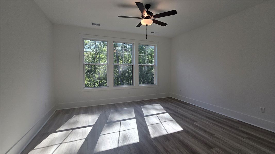 Three generous windows illuminate the primary bedr