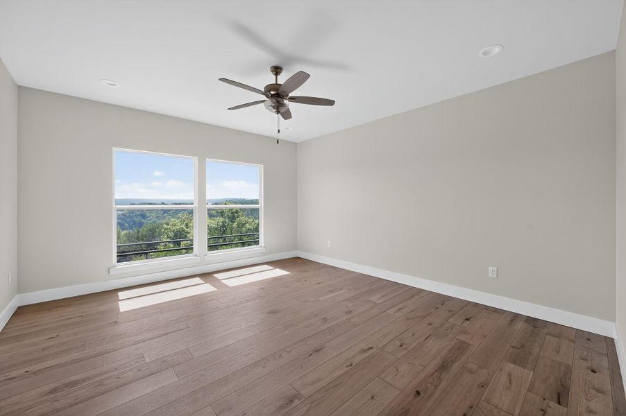 Rich wood-inspired floors and double windows framing leafy views define this versatile space.