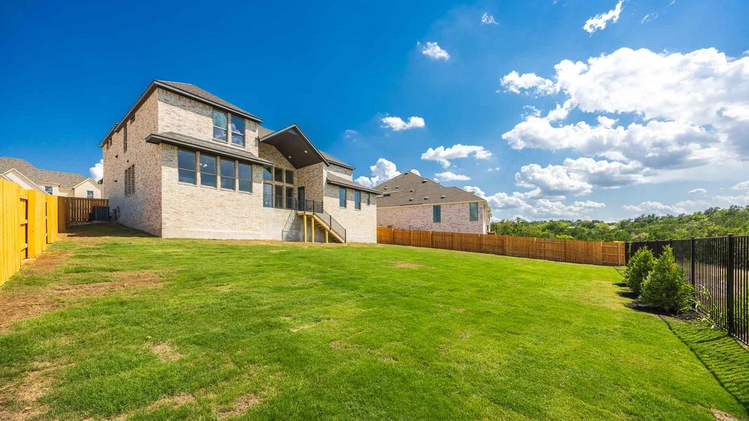 Back of house featuring a fenced backyard, brick siding, and a balcony Back of house featuring a fenced backyard, brick siding, and a balcony