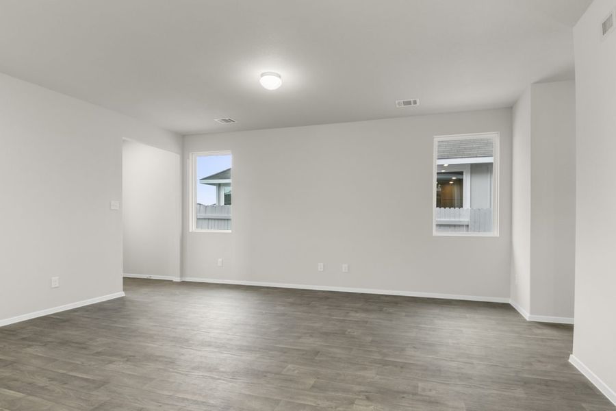 Image of a one story home living room with brown flooring and two windows
