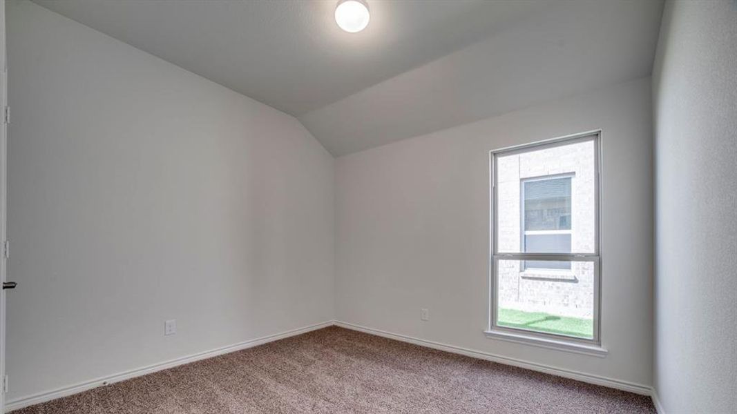 Unfurnished room featuring light colored carpet and vaulted ceiling