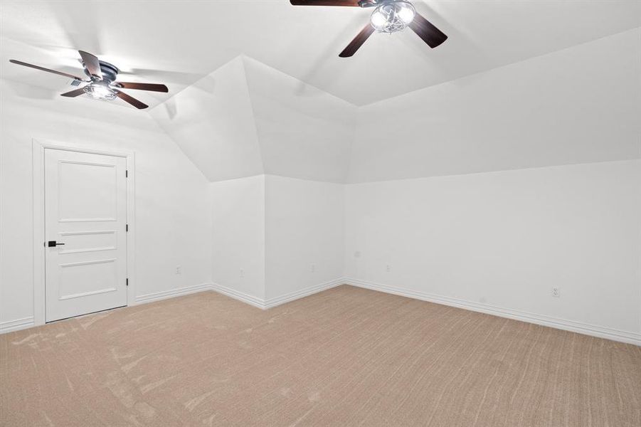 Bonus room featuring ceiling fan, light carpet, and vaulted ceiling Bonus room featuring ceiling fan, light carpet, and vaulted ceiling