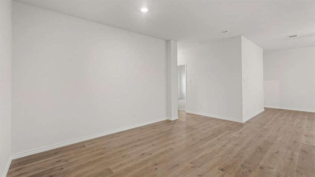 Spacious interior with light wood-finish flooring, white baseboards, and recessed lighting