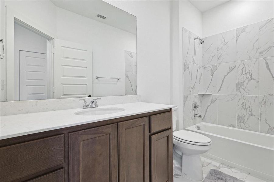 Full bathroom featuring tiled shower / bath combo, vanity, and toilet