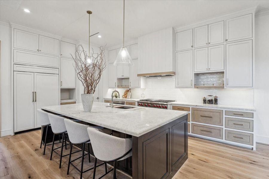 Another angle of the fabulous kitchen. Pop in a few barstools at the island for the perfect breakfast spot! Under-cabinet lighting and plug strips are another convenient addition to this space. The enormous walk-in pantry is neatly tucked away to the left.