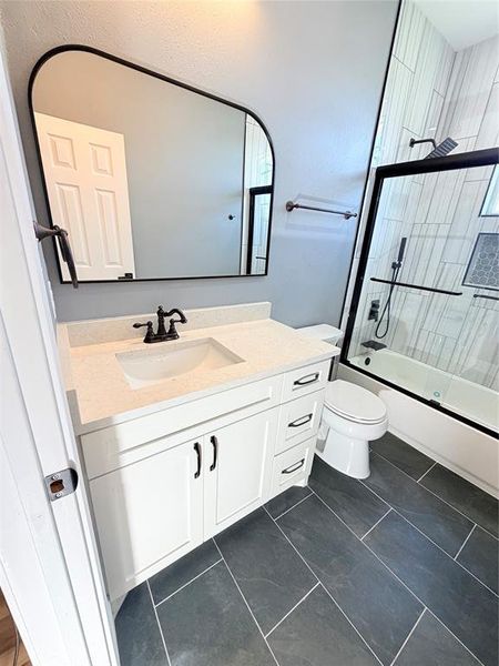 Modern bathroom featuring a white vanity with a light-colored countertop, an undermount sink, and black hardware