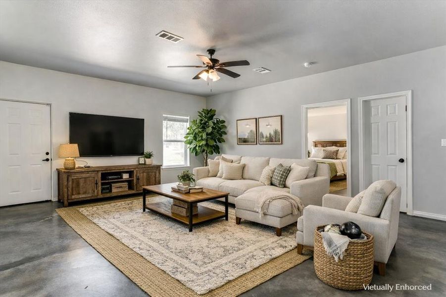 Spacious living area featuring light gray walls, a ceiling fan, and concrete flooring