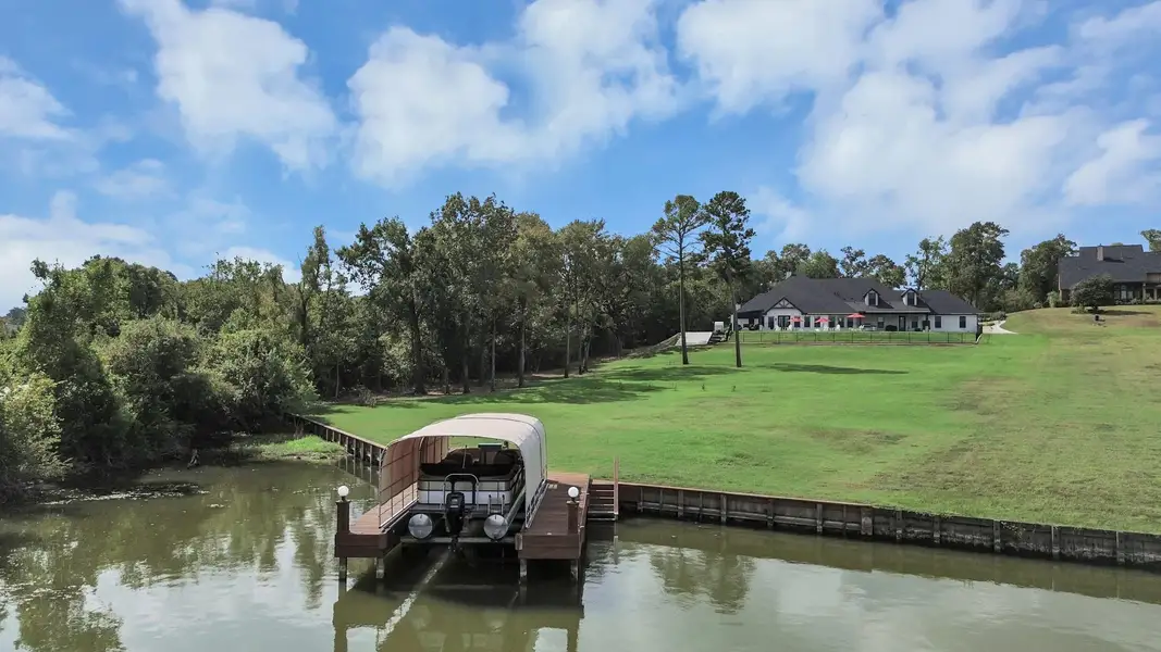 Expansive waterfront property with a private dock and spacious home, surrounded by lush greenery and serene views.