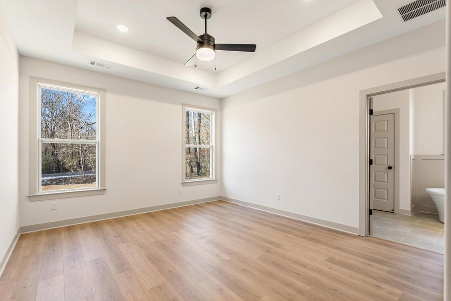 Spare room featuring ceiling fan, a tray ceiling, light wood-style floors, and recessed lighting