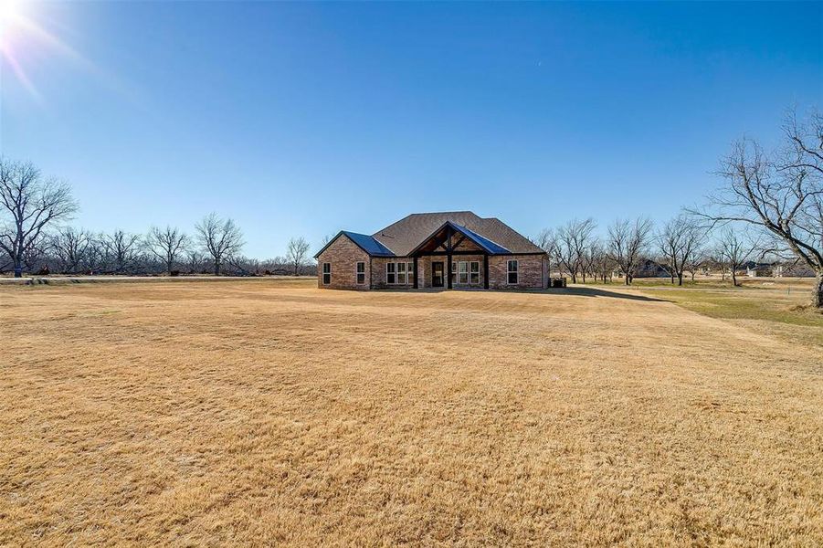 View of front of home with a front yard and a rural view