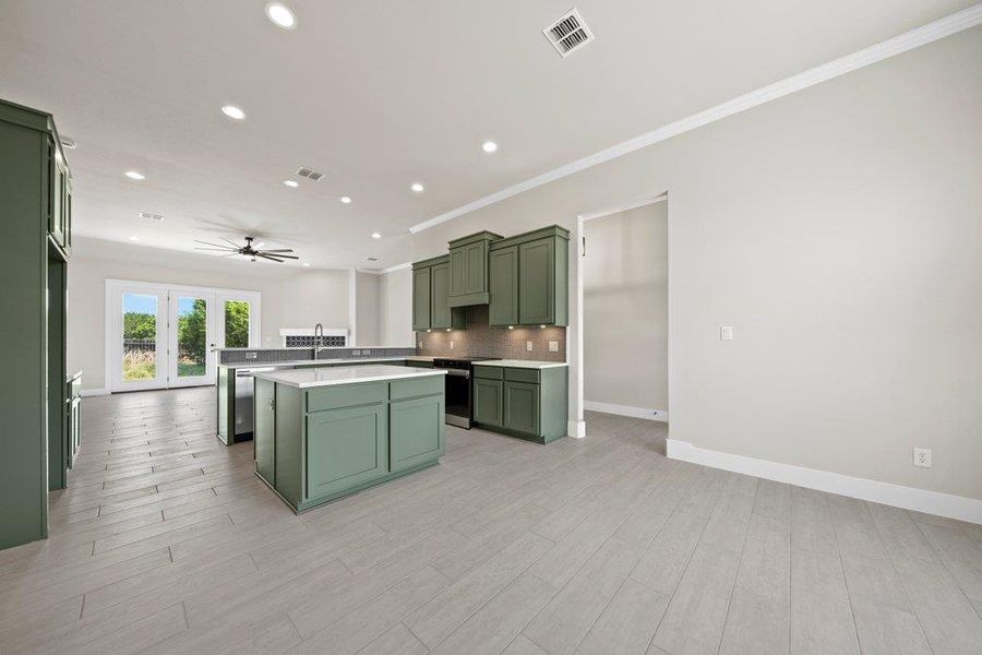 Kitchen with green cabinets, ceiling fan, recessed lighting, ornamental molding, and decorative backsplash Kitchen with green cabinets, ceiling fan, recessed lighting, ornamental molding, and decorative backsplash