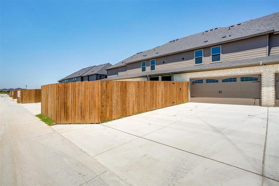 View of side of home with brick siding, driveway, and an attached garage