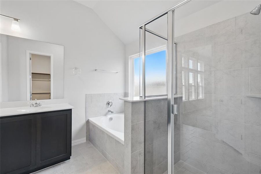 Bathroom featuring a bath, a shower stall, lofted ceiling, vanity, and tile patterned floors