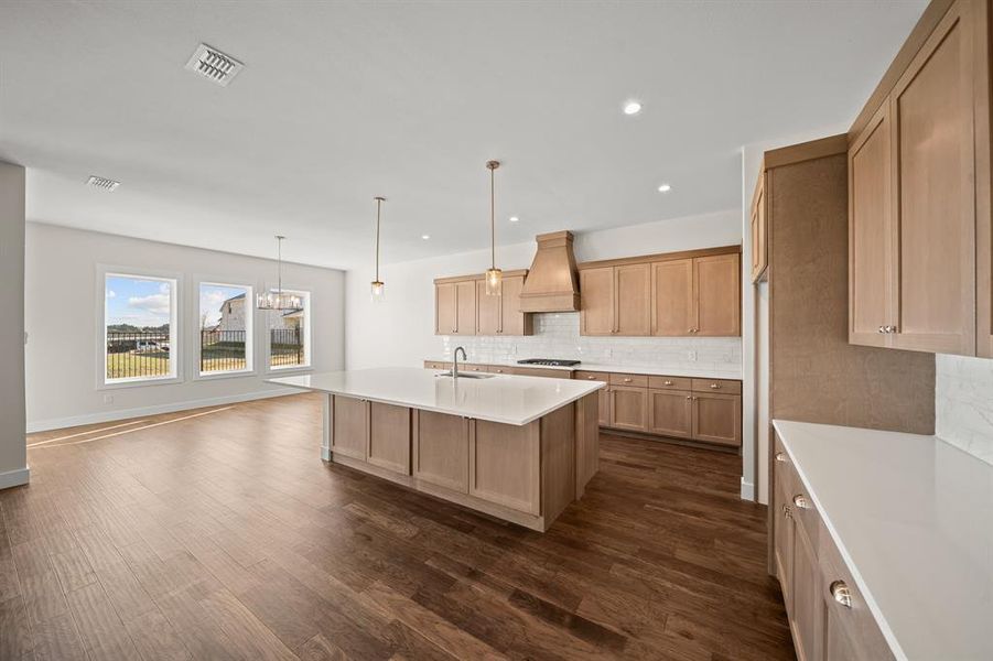 Kitchen with dark wood finished floors, backsplash, a kitchen island with sink, recessed lighting, and pendant lighting