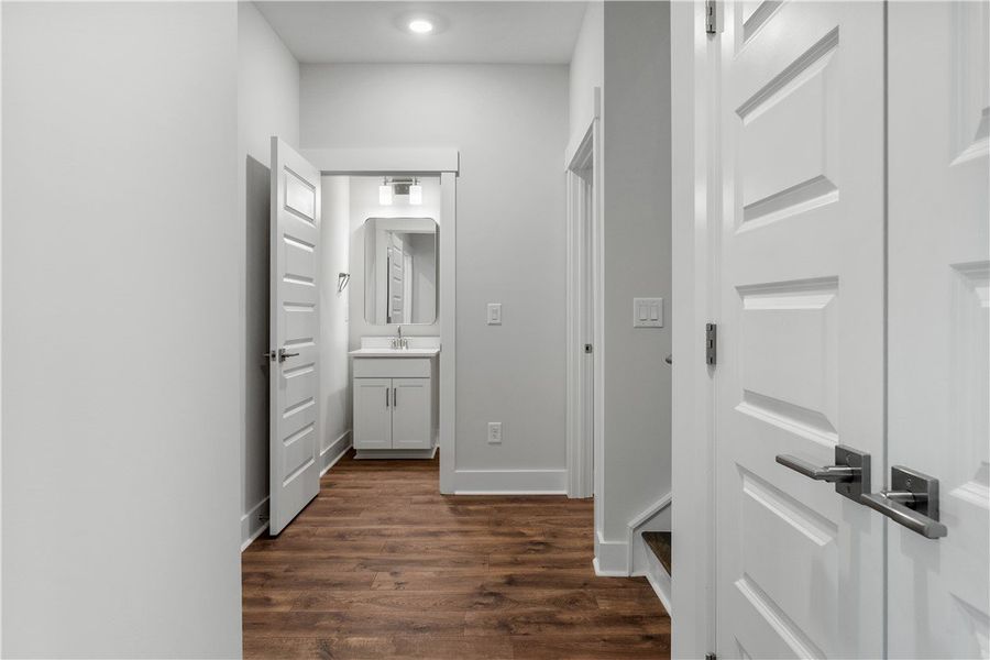 A well-lit hallway features rich hardwood flooring