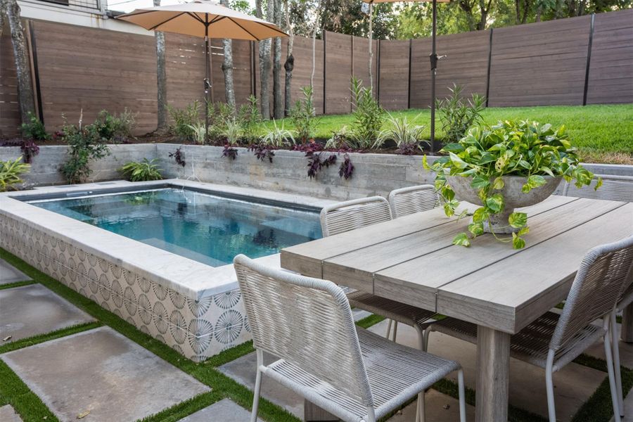 An inviting plunge pool anchors this private backyard featuring concrete pavers and wood fencing. An inviting plunge pool anchors this private backyard featuring concrete pavers and wood fencing.