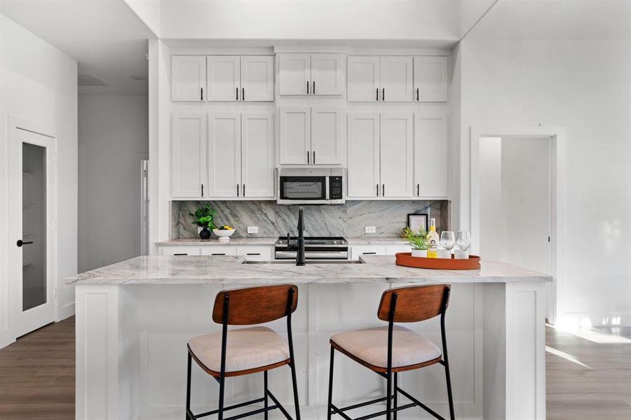 Kitchen featuring light stone countertops, white cabinetry, stainless steel appliances, and tasteful backsplash