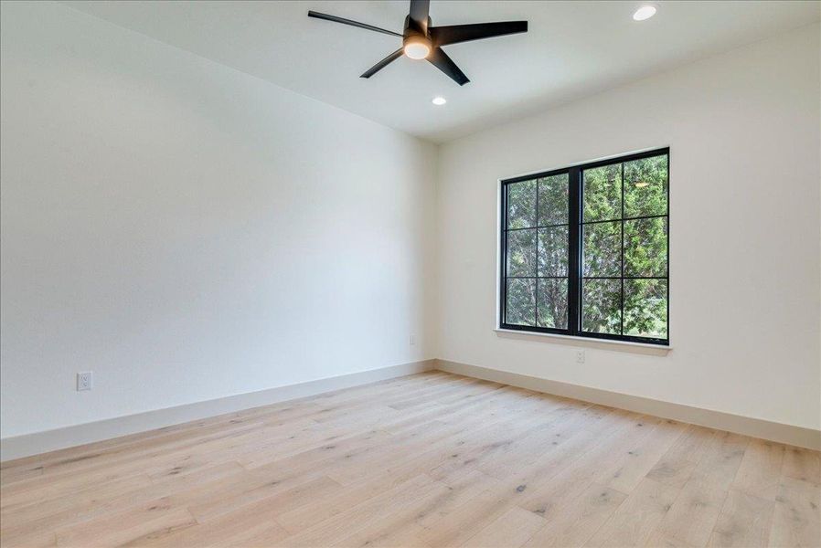 Naturally illuminated interiors boast light-toned wood flooring and a modern ceiling fan.