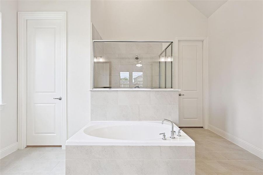 Bathroom featuring tile patterned flooring, vaulted ceiling, and independent shower and bath