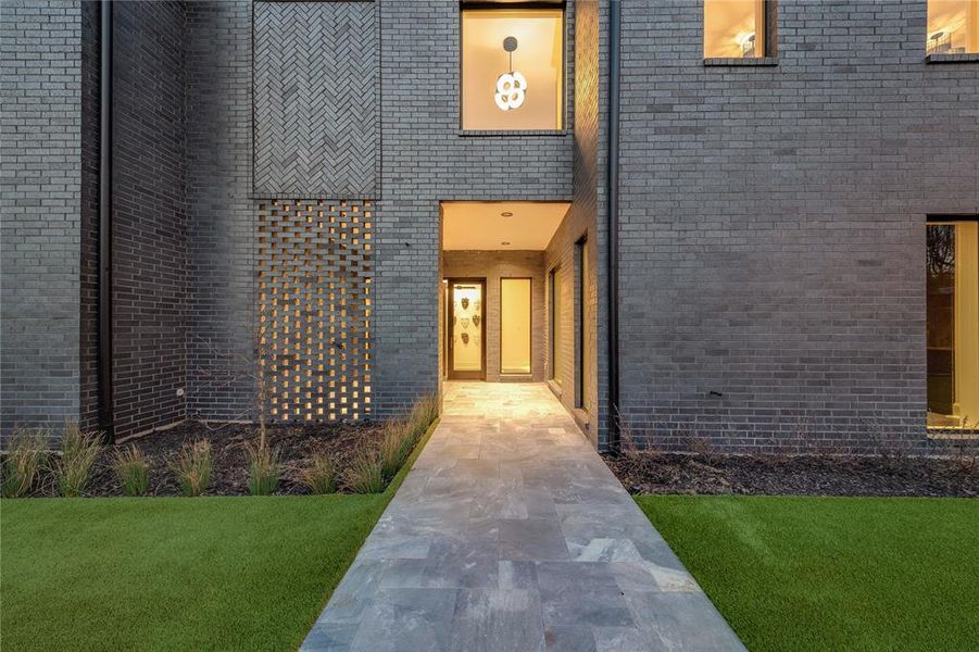 Property entrance with a yard and brick siding