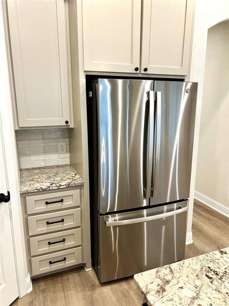 Kitchen featuring freestanding refrigerator, light wood-type flooring, and decorative backsplash Kitchen featuring freestanding refrigerator, light wood-type flooring, and decorative backsplash