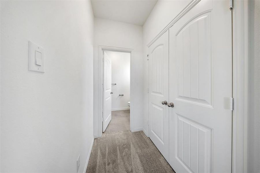 Hallway featuring light colored carpet and baseboards Hallway featuring light colored carpet and baseboards